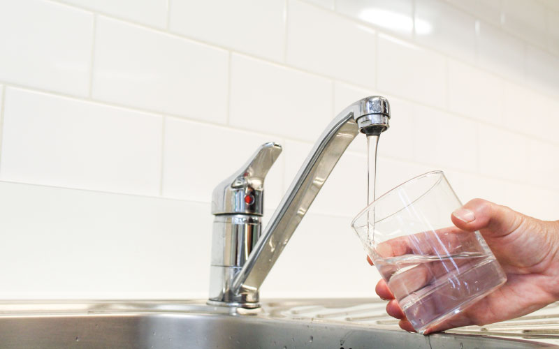Glass filling up with drinking water from tap. 