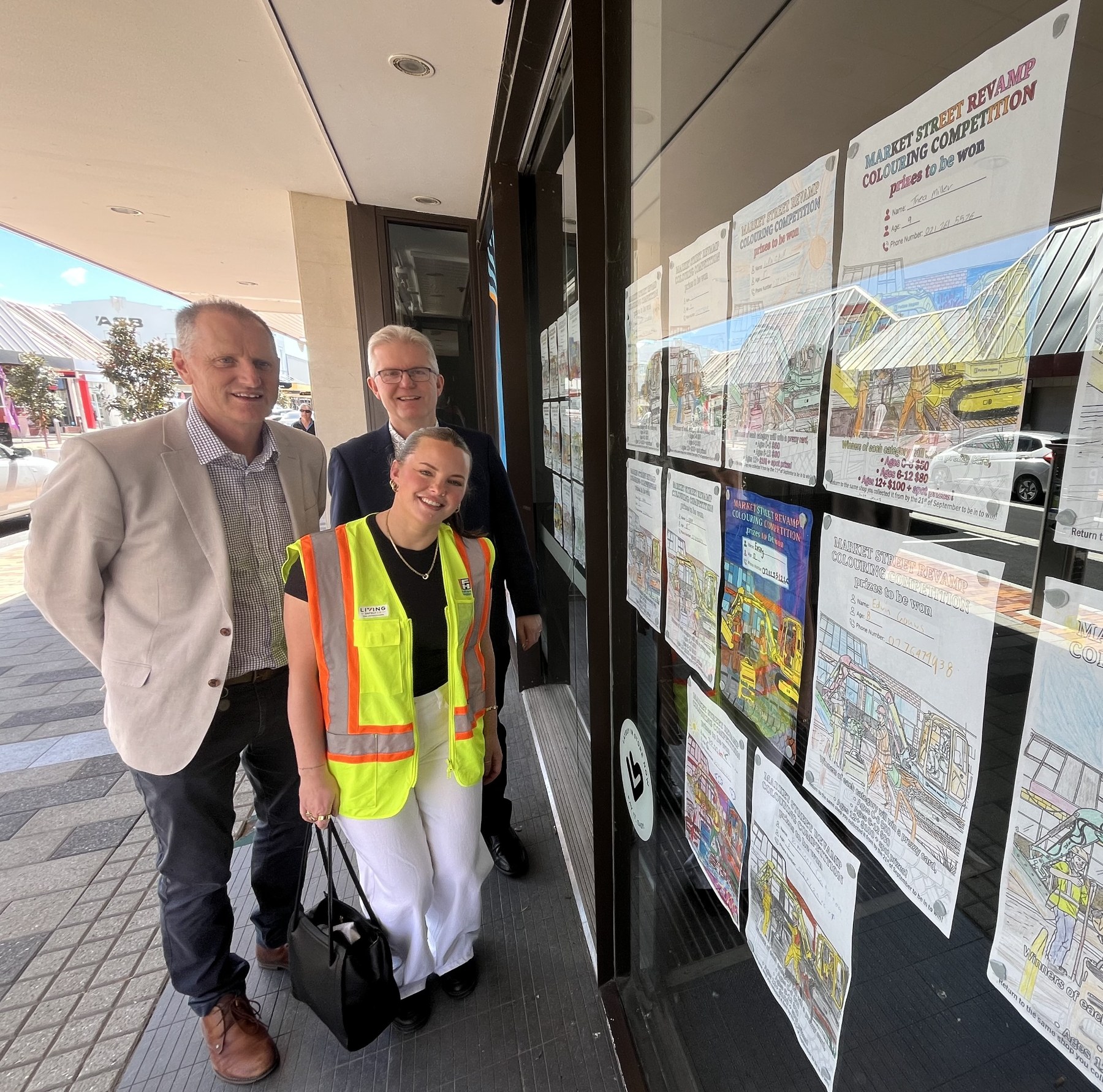 Deputy Mayor David Croad with Councillor Brian Dawson take a close look at entries in the Market Street colouring competition with Fulton Hogan’s Eva Edwards