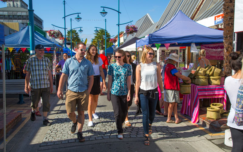 Group of people walking through Blenheim's main street at a market event. 
